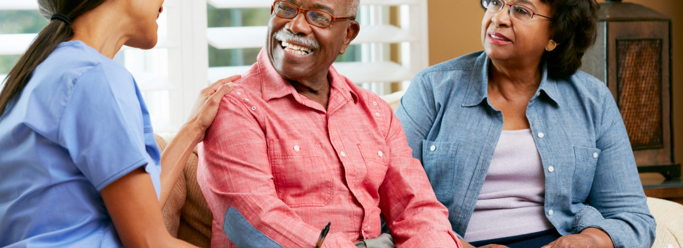 Nurse Making Notes During Home Visit With Senior Couple