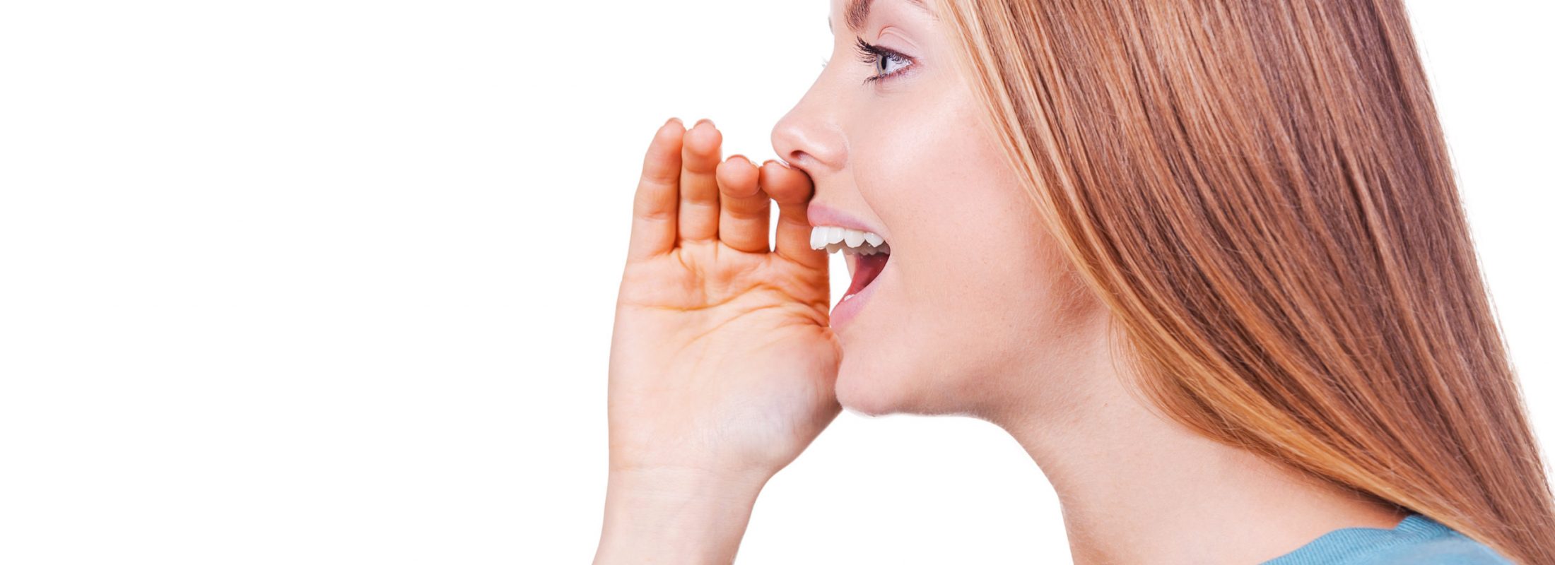 Sharing good news. Side view of beautiful young woman shouting and holding hand near mouth while standing isolated on white